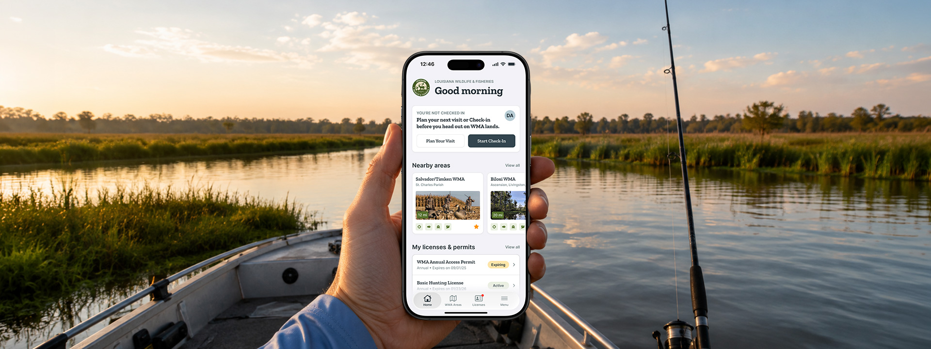 A hand holding a phone running the LWF app home screen, on a boat in a Louisiana marsh at sunrise with a fishing rod alongside